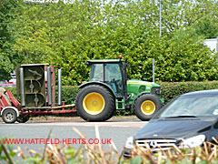 John Deere tractor towing a trailer with a grass cutting attachment