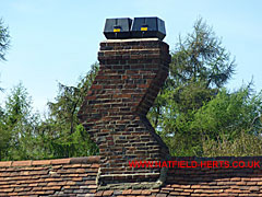 Crooked brick chimney with modern pots or extractor fans