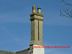 Tall brick twin stack joined at the summit and crowned with two pots