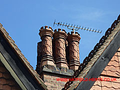 Ornate, tall, octagonal terracotta pots with crenallated crowns, three visible in first row of the stack