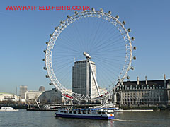 London Eye on a clear day from across the Thames with a pleasure boat in front